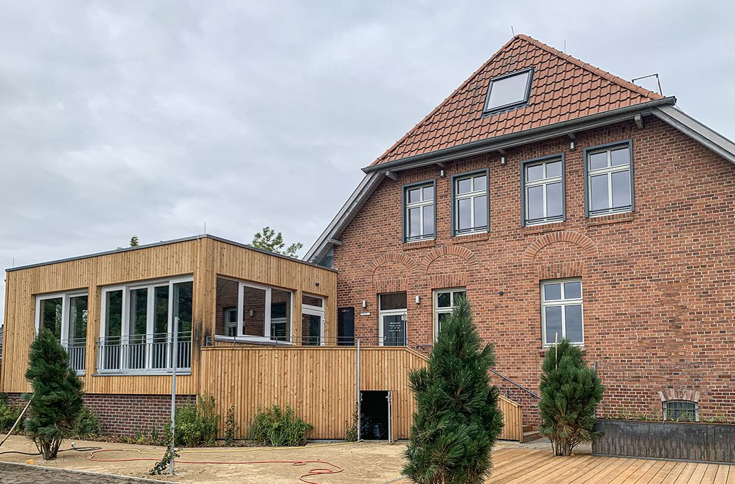 Saniertes Backsteingebäude des Gasthauses Sonnenufer mit modernem Holzanbau und Terrasse