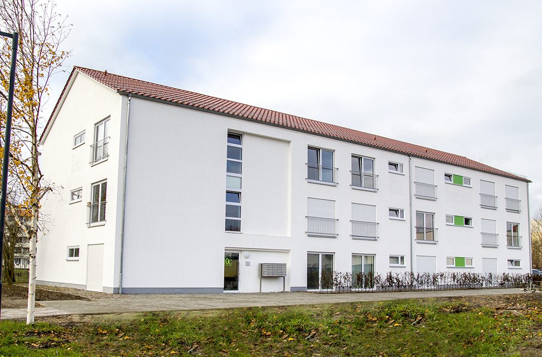 Modernes weißes Studentenwohnheim mit rotem Ziegeldach und grünen Akzenten