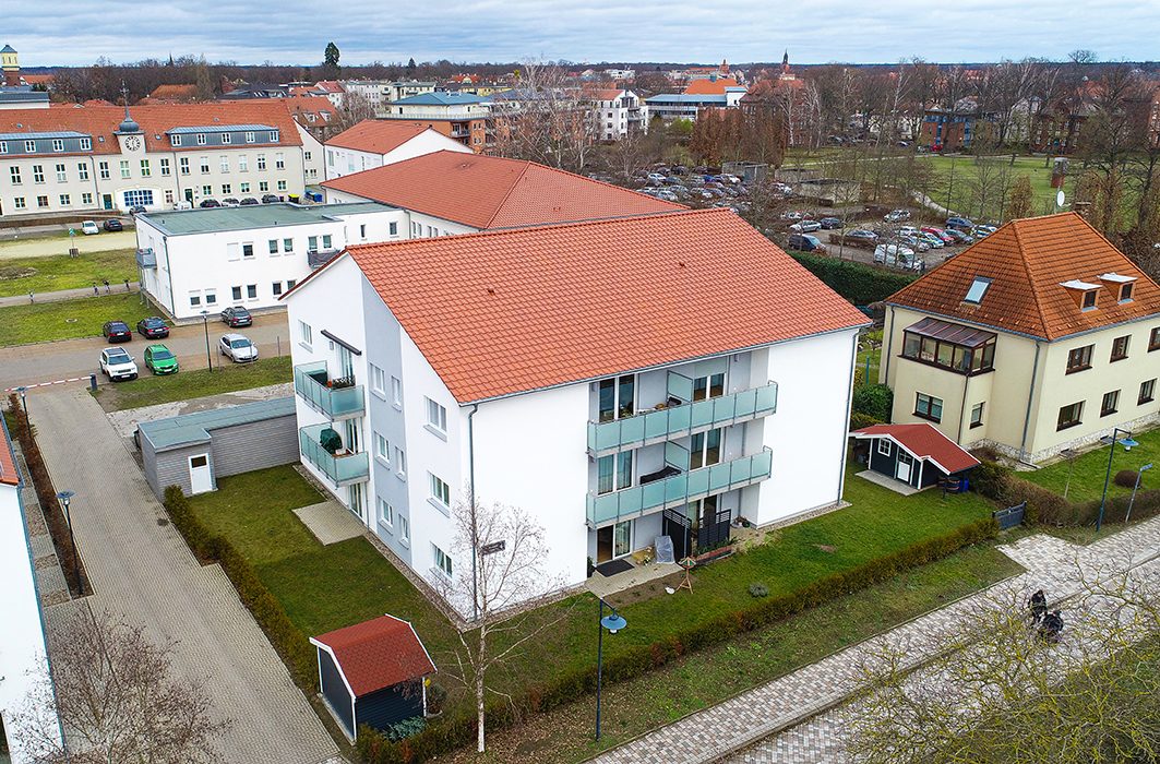 Modernes Mehrfamilienhaus mit rotem Ziegeldach und Glasbalkonen, Wohnanlage Heinrich-Mann-Straße aus der Luft
