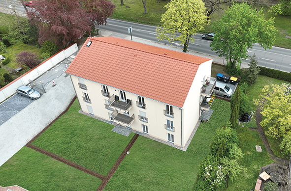 Luftaufnahme eines Mehrfamilienhauses mit rotem Satteldach und Garten, Wohnen am Tempelgarten Neuruppin